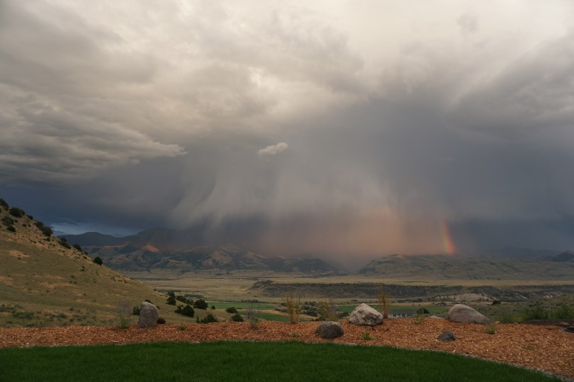 Big white clouds, rain, and a rainbow in a Montana Valley
